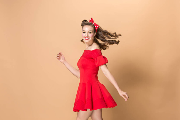 Beautiful young woman with pinup make-up and hairstyle. Studio shot on pastel background - Foto, imagen