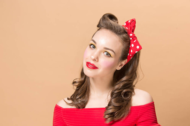 Beautiful young woman with pinup make-up and hairstyle. Studio shot on pastel background - 写真・画像