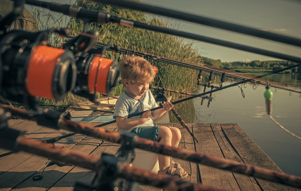 Baby sit on river pier with fishing rod and fishing - Φωτογραφία, εικόνα