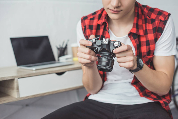 cropped view of teenager with retro film camera sitting at home - Фото, изображение