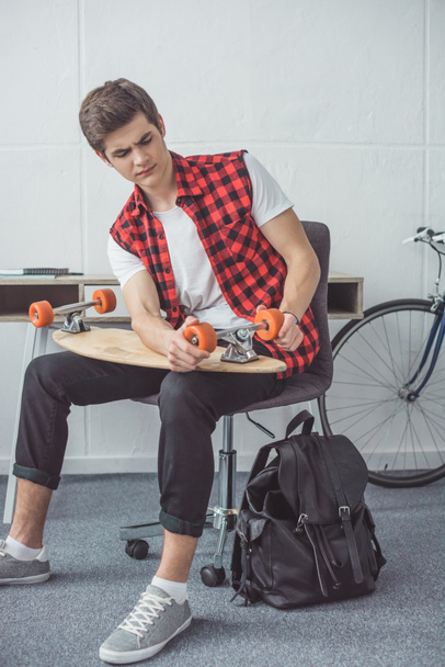 jeune skateboarder fixer son longboard à la maison
 - Photo, image