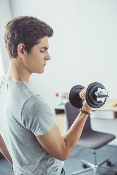young teenager exercising with dumbbell at home - Foto, Imagen