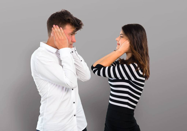 Молодая пара закрывает оба уха руками
 - Фото, изображение