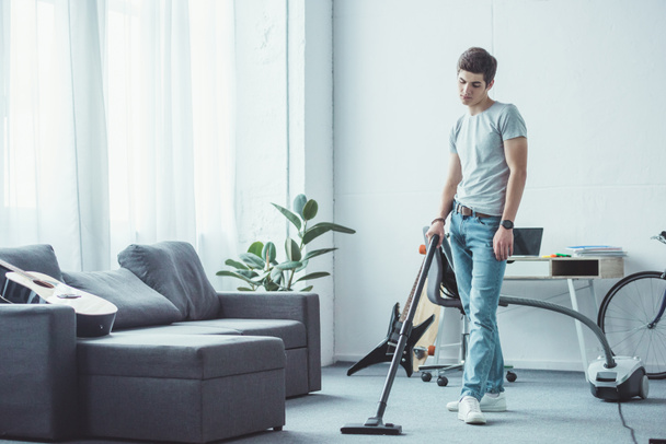 teen boy vacuuming floor with vacuum cleaner - Foto, imagen