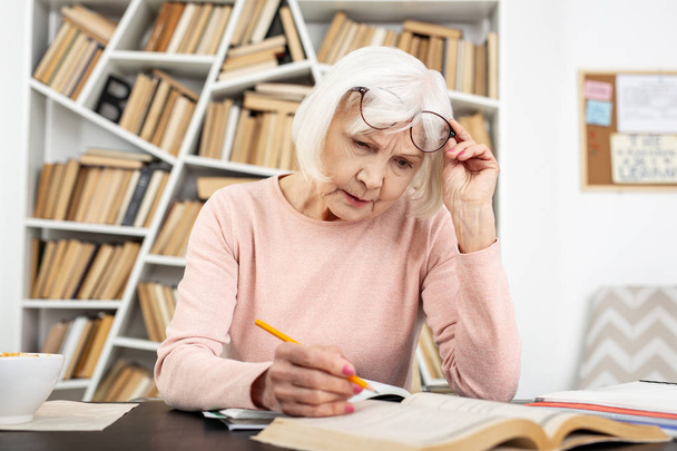 Attentive senior woman having trouble in study - Φωτογραφία, εικόνα