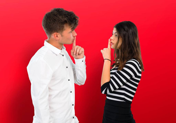 Giovane coppia mostra un segno di chiusura della bocca e silenzio gesto
 - Foto, immagini