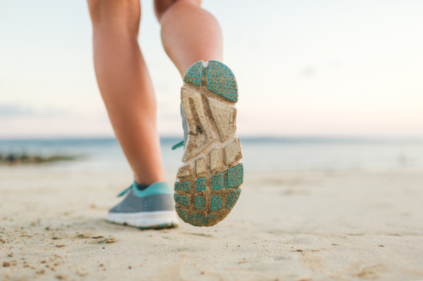 recortado disparo de jogger femenino corriendo en la playa de arena
  - Foto, Imagen