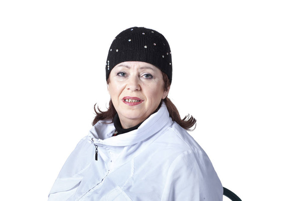 Повна жінка 60-65 років у білій спортивній куртці та спортивній кепці позує в студії на білому тлі
. - Фото, зображення