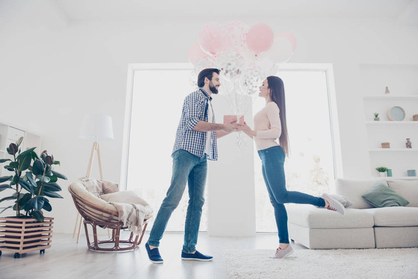 Profile side bottom view portrait of  cheerful stylish couple, man giving packed gift box case air ballons to lover in modern white flat, celebrating 14-february - Fotoğraf, Görsel