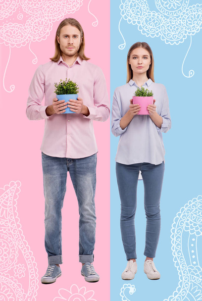 Full length of pleasant young couple holding pots with flowers - Foto, afbeelding