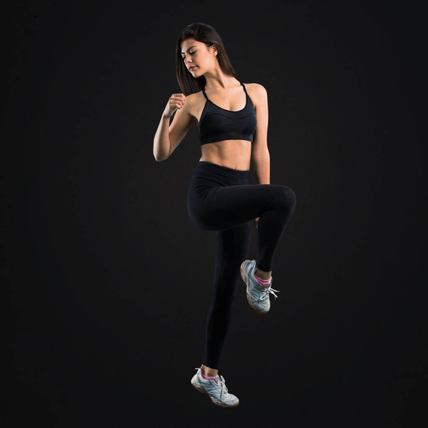 Young sport girl stretching on black background - Photo, image