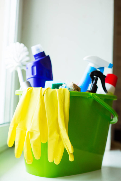 Secchio verde in plastica con prodotti per la pulizia sulla finestra. Attrezzature per la pulizia della casa
 - Foto, immagini