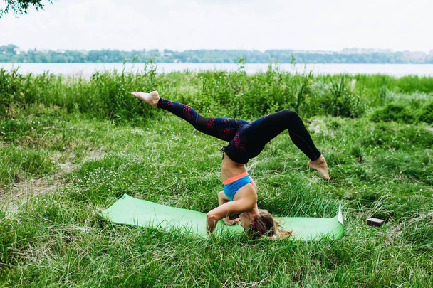 Sportive young woman in sportswear doing yoga exercise outdoors - Foto, Bild