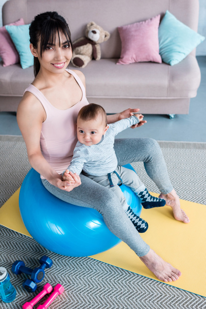 jeune belle mère assise sur ballon en forme avec petit enfant à la maison
 - Photo, image