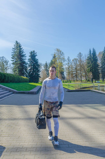 Homem forte em roupas esportivas brancas e luvas com um saco no Parque
 - Foto, Imagem