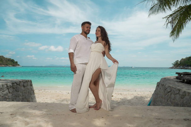 attraktives junges Paar auf der tropischen Insel. schöne Frau und Mann in weißen Kleidern umarmen einander und genießen trpoical Urlaub Kurzurlaub - Foto, Bild
