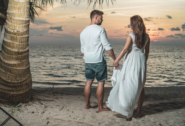美しい日没時に熱帯の砂浜で魅力的なロマンチックなカップル - 写真・画像