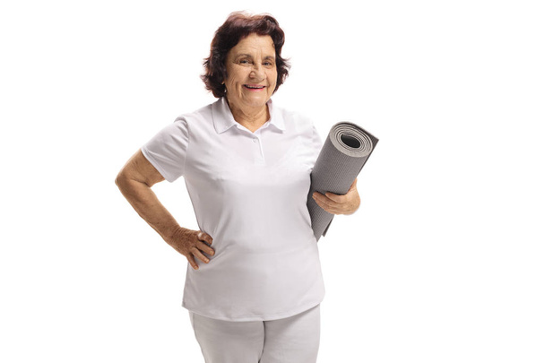 Mujer mayor sosteniendo una esterilla aislada sobre fondo blanco
 - Foto, imagen
