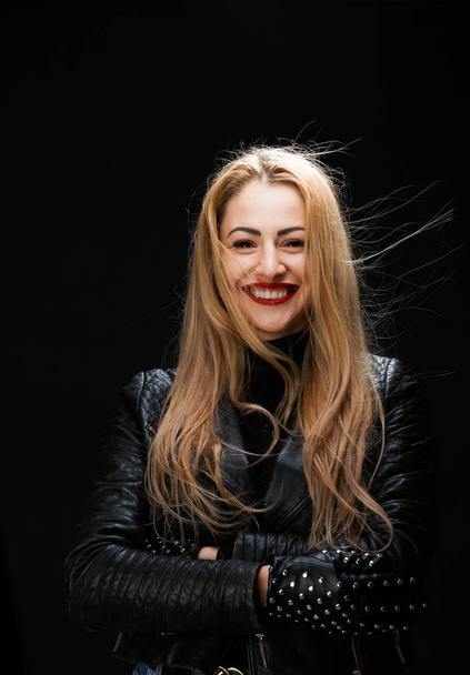 Photo of smiling blonde in leather jacket with arms crossed at waist - Fotó, kép