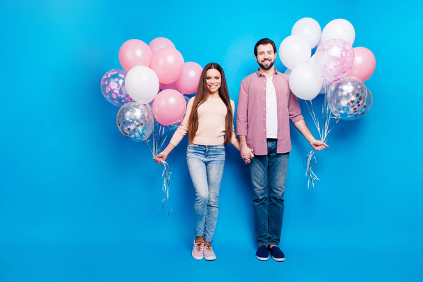 Full size fullbody portrait of stylish trendy partners holding hands having pink and white air balloons in arms wearing sneakers shoes pants isolated on bright background - Foto, imagen