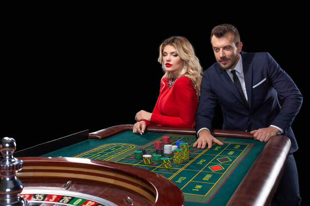 Mooi en goed geklede paar spelen roulette in het casino - Foto, afbeelding