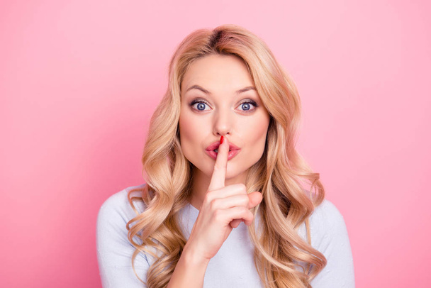 Shhh! Portrait of pretty mysterious girl in casual outfit showing silence sign holding forefinger on lips having curly hair modern hairdo isolated on pink background - Photo, Image