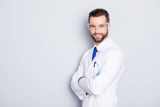 Portrait with copy space, empty place of joyful half-turned scientist with stubble in white outfit with tie having his arms crossed looking at camera isolated on grey background - Foto, Imagen