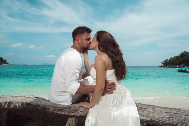 Pohledný mladý pár na tropickém ostrově. Krásná žena a muž na sobě bílé oblečení, objímat a těší trpoical svátky dovolenou útěk - Fotografie, Obrázek