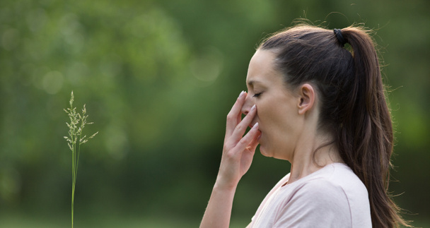 Portret młoda kobieta, kichanie w parku z zielonym tłem. Alergia na pyłki w koncepcji wiosna - Zdjęcie, obraz