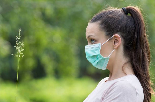 Korkmuş kadın çimlere arıyorsunuz ve parkta alerjenler panik reaksiyon maskesi. Polen alerji kavramı - Fotoğraf, Görsel