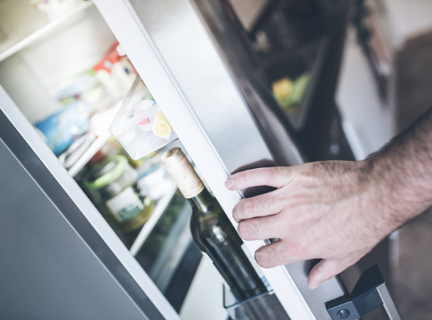 hand opening refrigerator door in kitchen - Fotografie, Obrázek