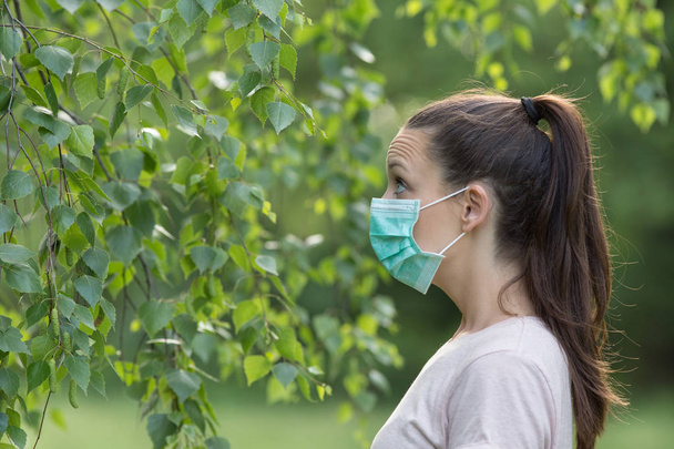 マスク ツリーを見て、公園のアレルゲンに異常な反応を持っていることを恐れて女性。花粉アレルギーの概念 - 写真・画像