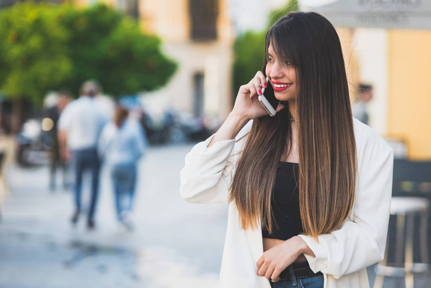 Retrato de una hermosa joven usando su teléfono celular en la calle
 - Foto, Imagen