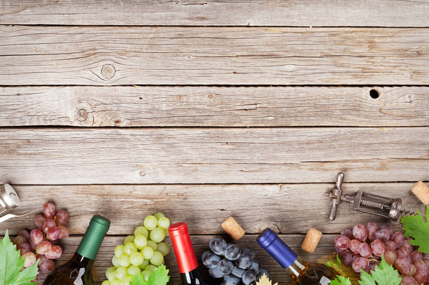 Μπουκάλια κρασιού και τα σταφύλια σε ξύλινο τραπέζι. Το Top view με χώρο για το κείμενό σας - Φωτογραφία, εικόνα