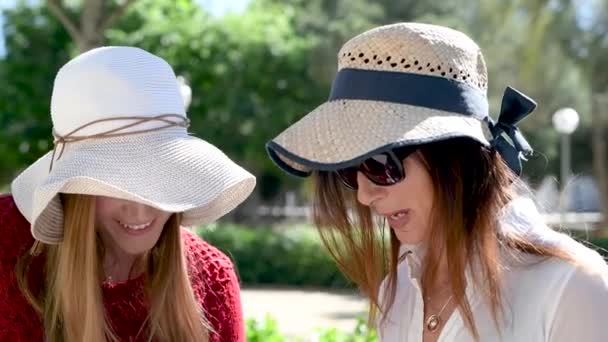twee vrouwelijke toeristen in stro hoeden op straat op zonnige dag - Video