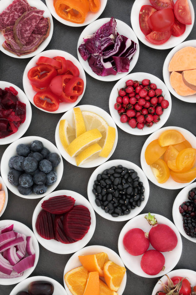 Υγιεινή διατροφή με φρούτα, λαχανικά και όσπρια σε πορσελάνη κύπελλα σε σχιστόλιθο φόντο, τροφές πολύ πλούσιες σε αντιοξειδωτικές ουσίες, ανθοκυανίνες, φυτικές ίνες, βιταμίνες και μέταλλα. - Φωτογραφία, εικόνα