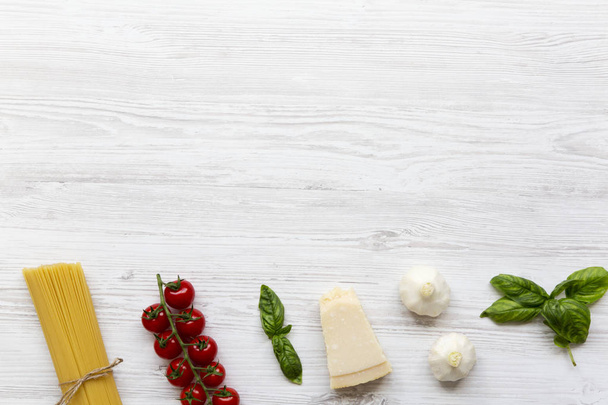 Esparguete italiano, tomates, parmesão, manjericão e alho. Suplementos para cozinhar massa, vista superior. Espaço para texto
. - Foto, Imagem