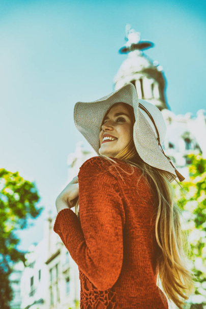 Happy beautiful blonde girl with straw hat enjoying visiting city. - Фото, зображення