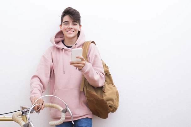 молодой студент с рюкзаком и велосипедом на белой стене
 - Фото, изображение