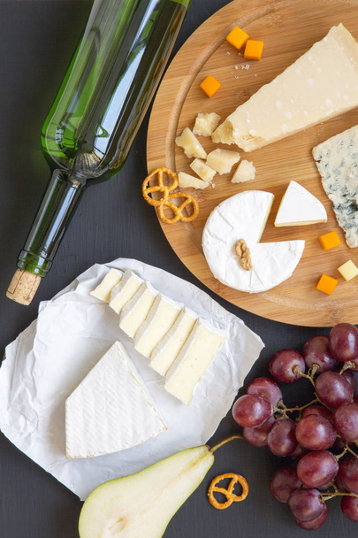 Plateau de fromage avec vin, fruits, bretzels et noix sur fond sombre, vue sur le dessus. D'en haut. Pose plate
. - Photo, image