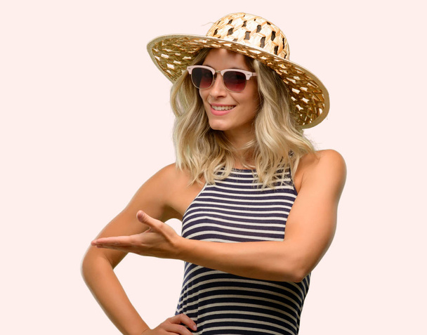 Fiatal nő segítségével napszemüveg viselése nyári kalap valami lévő üres kézzel - Fotó, kép
