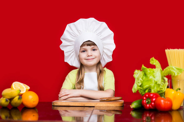 Şef Tekdüzen mutlu küçük kız mutfakta sebze keser. Çocuk Şef. Vejetaryen. Pişirme işlemi kavramı - Fotoğraf, Görsel