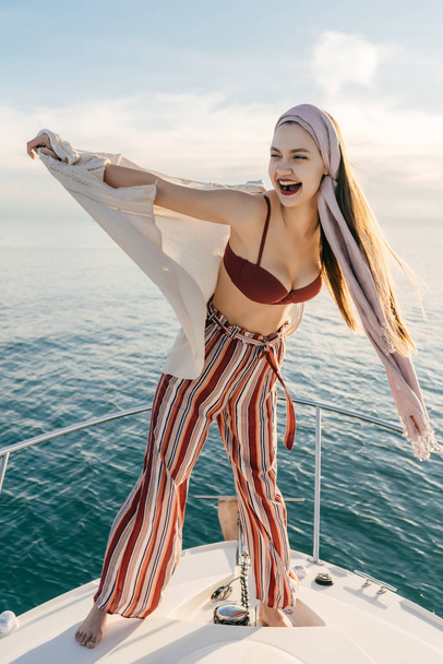a luxurious stylish young woman in fashionable pants swims on her white yacht on the Caribbean sea, enjoys a rich life and vacation - Valokuva, kuva