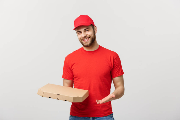 Lieferkonzept: junger kaukasischer, gutaussehender Pizzabote mit Pizzakartons vor grauem Hintergrund - Foto, Bild