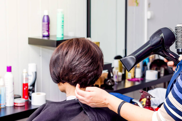 Hiustenkuivaaja käsissä kampaaja. Kauniit kampaukset kauneushoitolassa
 - Valokuva, kuva
