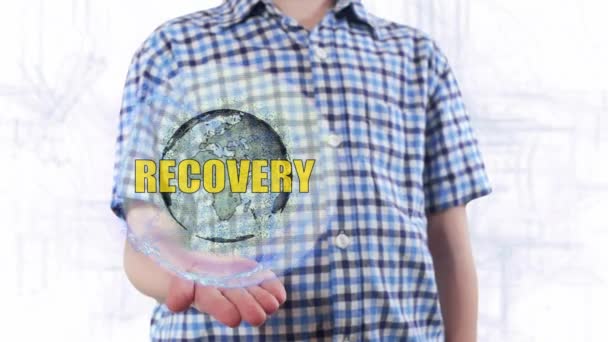 Young man shows a hologram of the planet Earth and text Recovery - Footage, Video