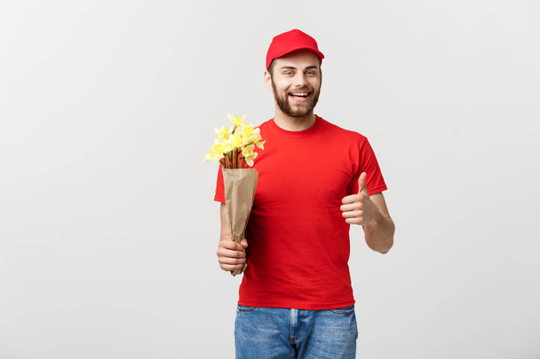Έννοια της παράδοσης: Πορτρέτο του ευτυχισμένος λουλούδι παράδοση από τον άνθρωπο εκμετάλλευση όμορφη ανθοδέσμη λουλουδιών και δείχνει τον αντίχειρα σε λευκό φόντο - Φωτογραφία, εικόνα