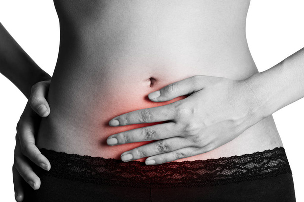 Woman holding her stomach with red highlighted on pain area, black and white color isolate on white background. - Foto, afbeelding
