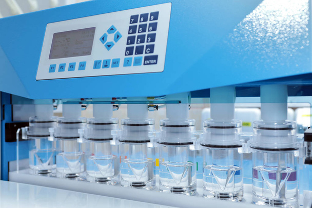 Obtaining precise results of analyzes of difficult soluble drugs. The girl is doing tests in pharmaceuticals. Sotax Ag. Production and analysis of tablets. Modern pharmaceuticals. Factory producing tablets. Laboratory of quality. - Фото, изображение