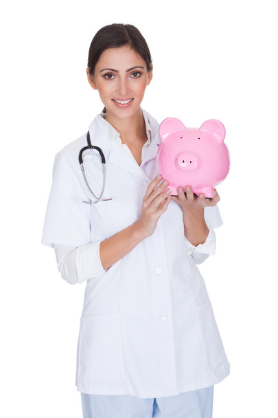 Young Female Doctor Holding Piggy Bank - Fotografie, Obrázek